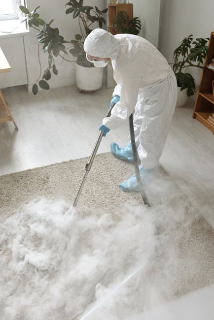 Close-up of a modern dry vacuum cleaner with a transparent dust container filled with debris and bubbles, connected to a flexible, patterned hose attached to a cleaning head. The vacuum is positioned 